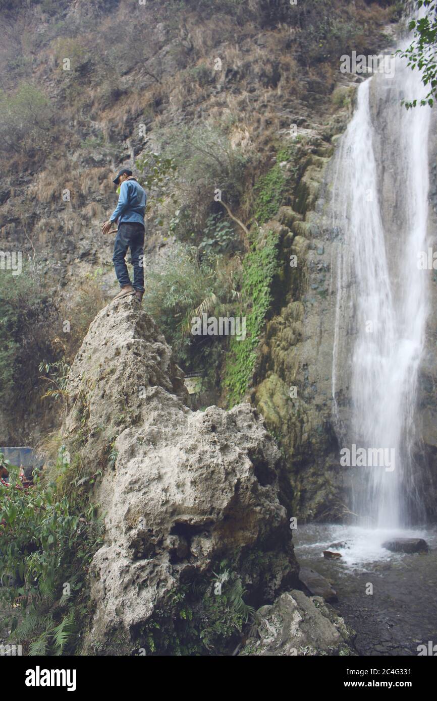 Reisender steht auf einem Felsen in der Nähe von Wasserfall in azad Kaschmir, Pakistan Stockfoto