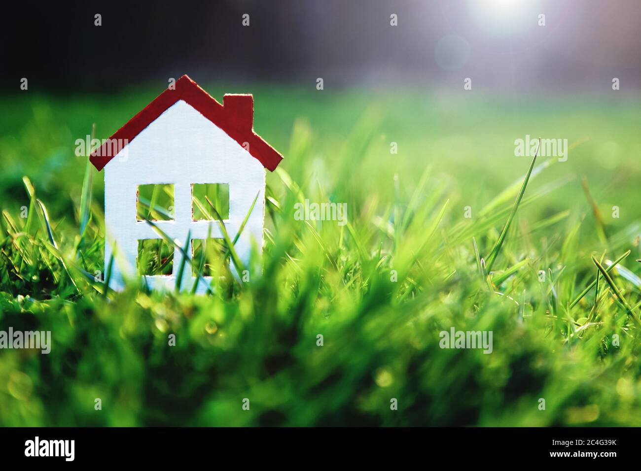 Kleines weißes Spielzeughaus auf grünem Gras in Sonnenschein mit Kopieplatz für Immobilienkauf, Hypotheken, Hausbesitzer-Versicherung, Haus und Grundstück zum Verkauf Mock Stockfoto