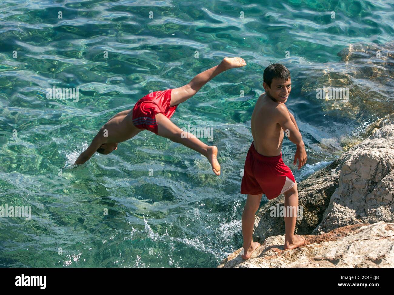 Türkische Jungs tauchen vor der römischen Hafenmauer in die Antalya-Bucht in der Altstadt von Kaleici in Antalya in der Türkei. Stockfoto