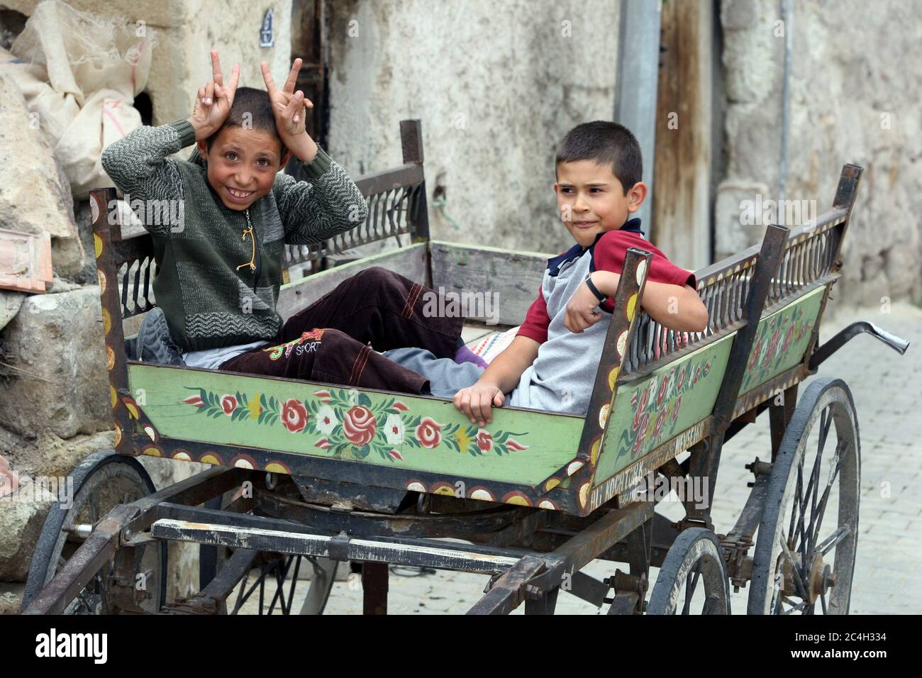 Türkische Jungen sitzen in einem Holzwagen auf einer Straße in der Stadt Goreme in der Region Kappadokien in der Türkei. Stockfoto