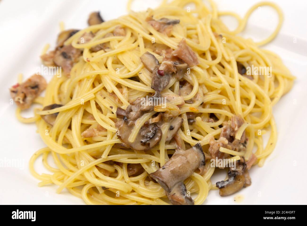 Spaghetti Carbonara, hergestellt mit Parmaschinken (Prosciutto di Parma) und Pilzen. Der Schinken wird rund um die Stadt Parma in Norditalien hergestellt. Stockfoto