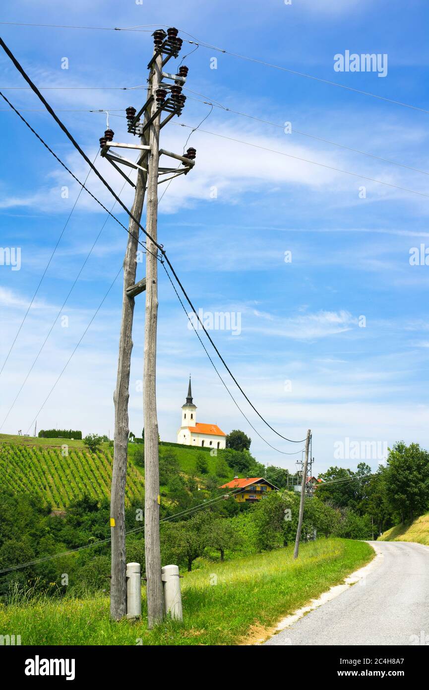 Sveti Urban, Nähe Maribor, Slowenien, Europa - Hügel mit Weinberg und kleine christliche Kirche auf der Spitze. Elektrischer Pol und Straße im Vordergrund Stockfoto