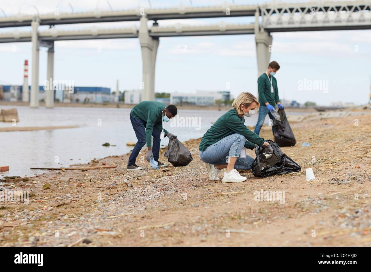 Gruppe von Freiwilligen, die das Ufer des Flusses vom Müll säubern Stockfoto