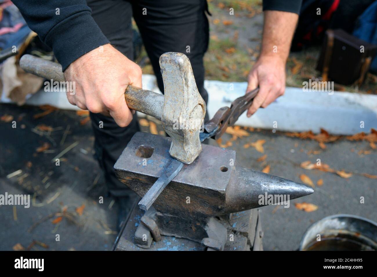 Schmiede Hände halten Pinzette und Hammer Schmieden einer Metall-Billet, Klinge eines Messers, auf einem Amboss Stockfoto