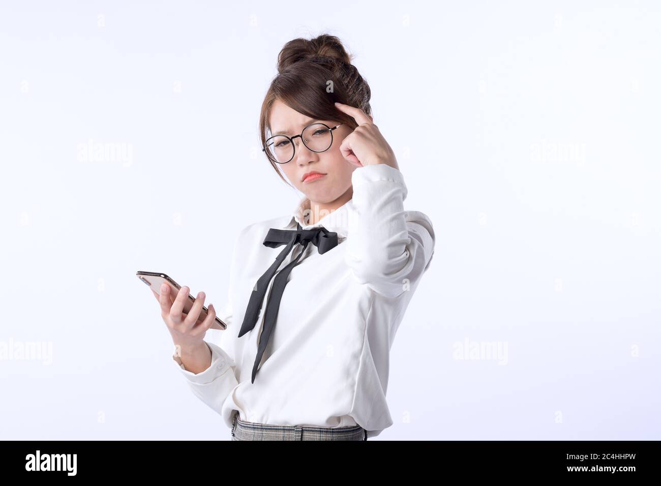 Porträt eines jungen Mädchens, das ein Handy hält und sich um etwas mit soliertem weißen Hintergrund sorgt. Negative menschliche Emotion Gesichtsausdruck f Stockfoto