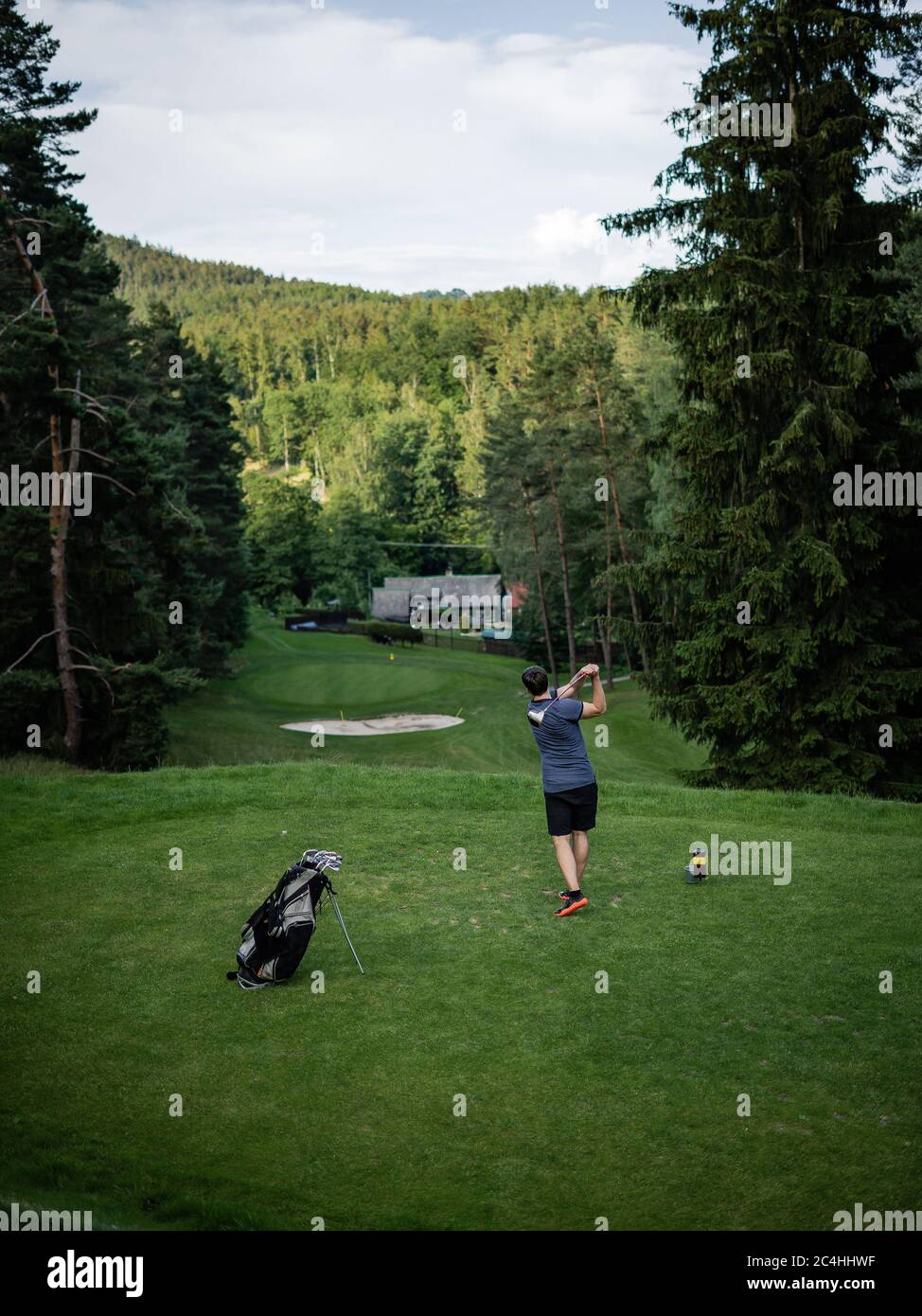 Mann, der Golf auf einem Golfplatz in der Sonne spielt. Männlicher Spieler auf einem professionellen Golfplatz. Golfer mit Golfschläger, der einen Schuss schieß Stockfoto