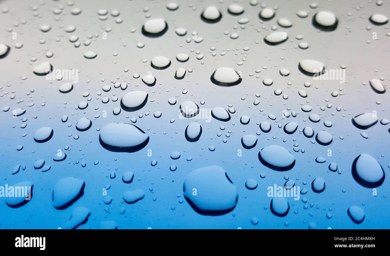 Spritzer von Regentropfen auf einer Autoscheibe nach einem Sturm. Abgewinkelter Blickwinkel für Schärfentiefe und selektiven Fokus. Stockfoto