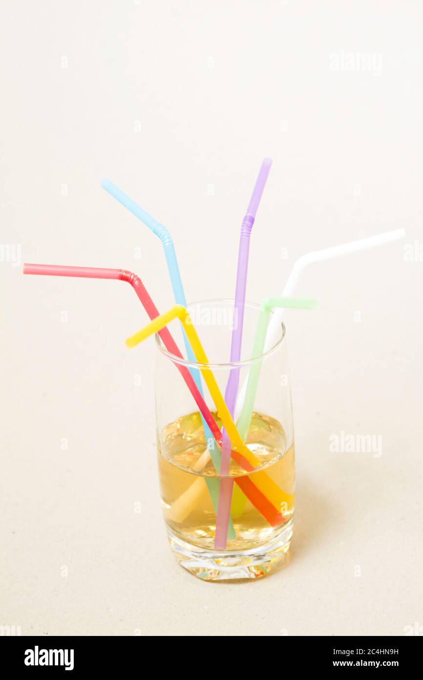 Bunte Röhren in einem Glas mit einem gelben Getränk - Seitenansicht Stockfoto