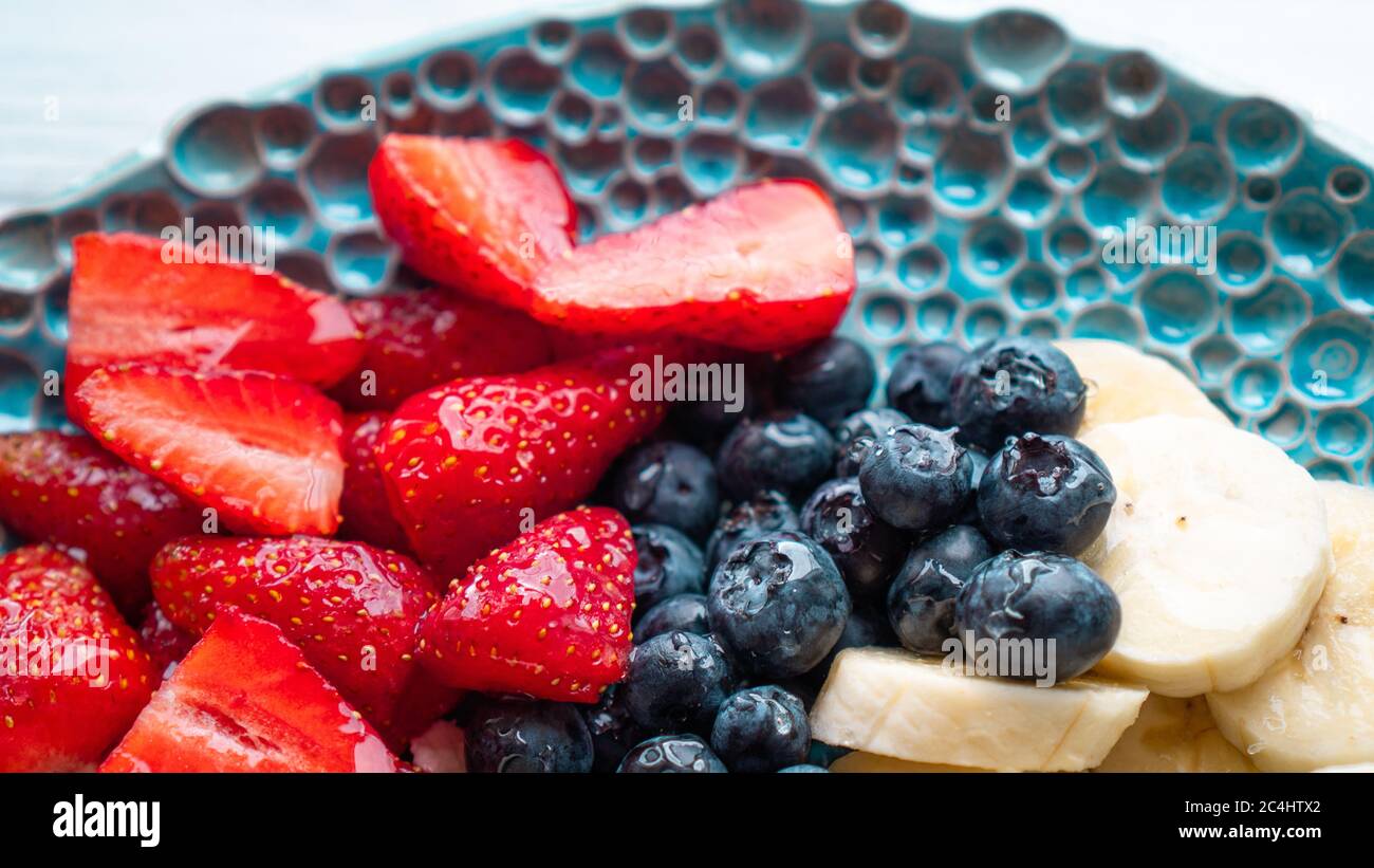 Morgenvergnügen. Gesundes Sommerfrühstück. Beeren Früchte Erdbeere Heidelbeere Banane und Honig. Vitamin-Snack Stockfoto