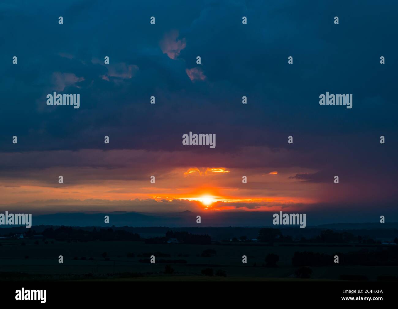 Dramatisch bedrohlicher Gewitterhimmel mit orangefarbenem Sonnenuntergang, Blick von East Lothian, Schottland, Großbritannien nach Fife Stockfoto