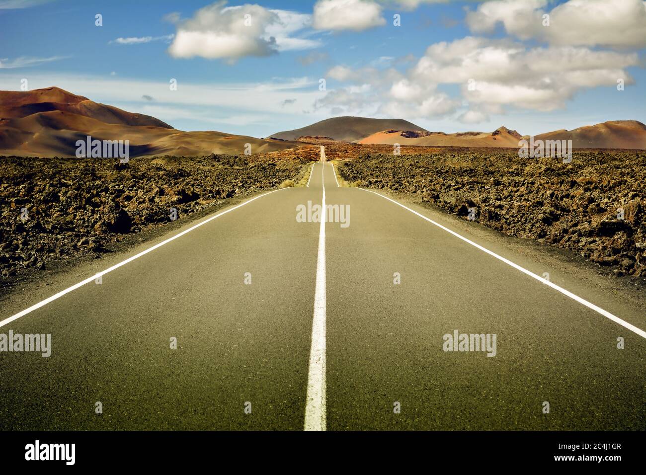 Keine Menschen, keine Tiere, keine Vegetation. Nur ich, die Straße und der blaue Himmel in der Mitte eines vulkanischen Lavameeres Stockfoto