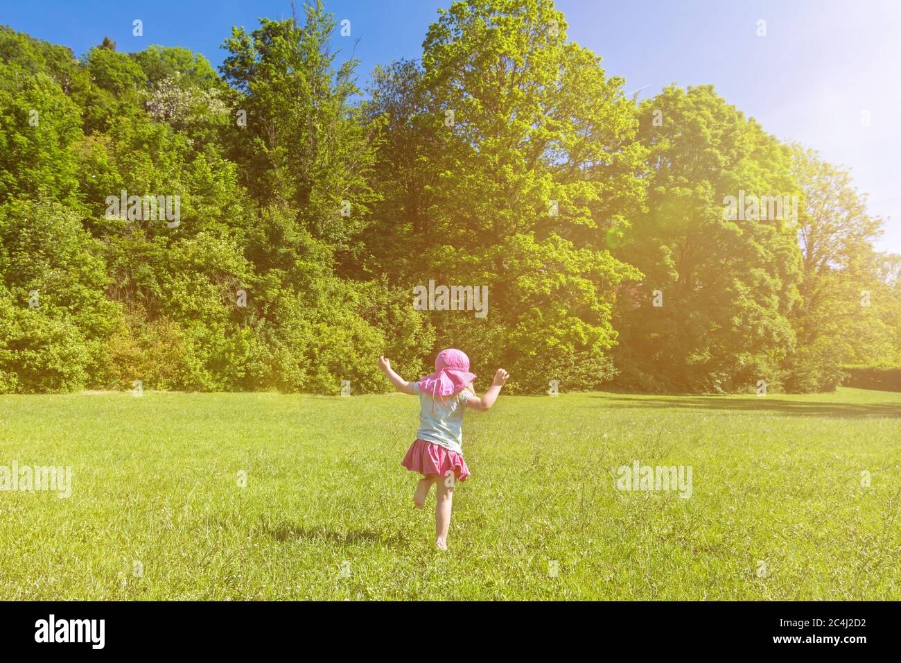 Junge glückliche Kind Spaß und Tanz auf einer grünen Wiese im Frühjahr an einem sonnigen Tag Stockfoto