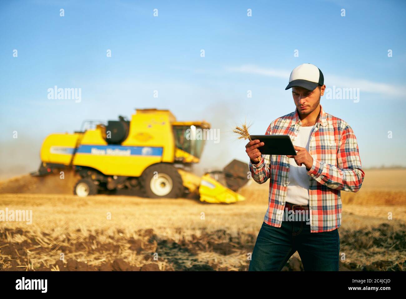 Präzisionslandwirtschaft. Landwirt hält Tablet für Mähdrescher Führung und Steuerung mit modernen Automatisierungssystem. Agronom mit Online-Daten Stockfoto