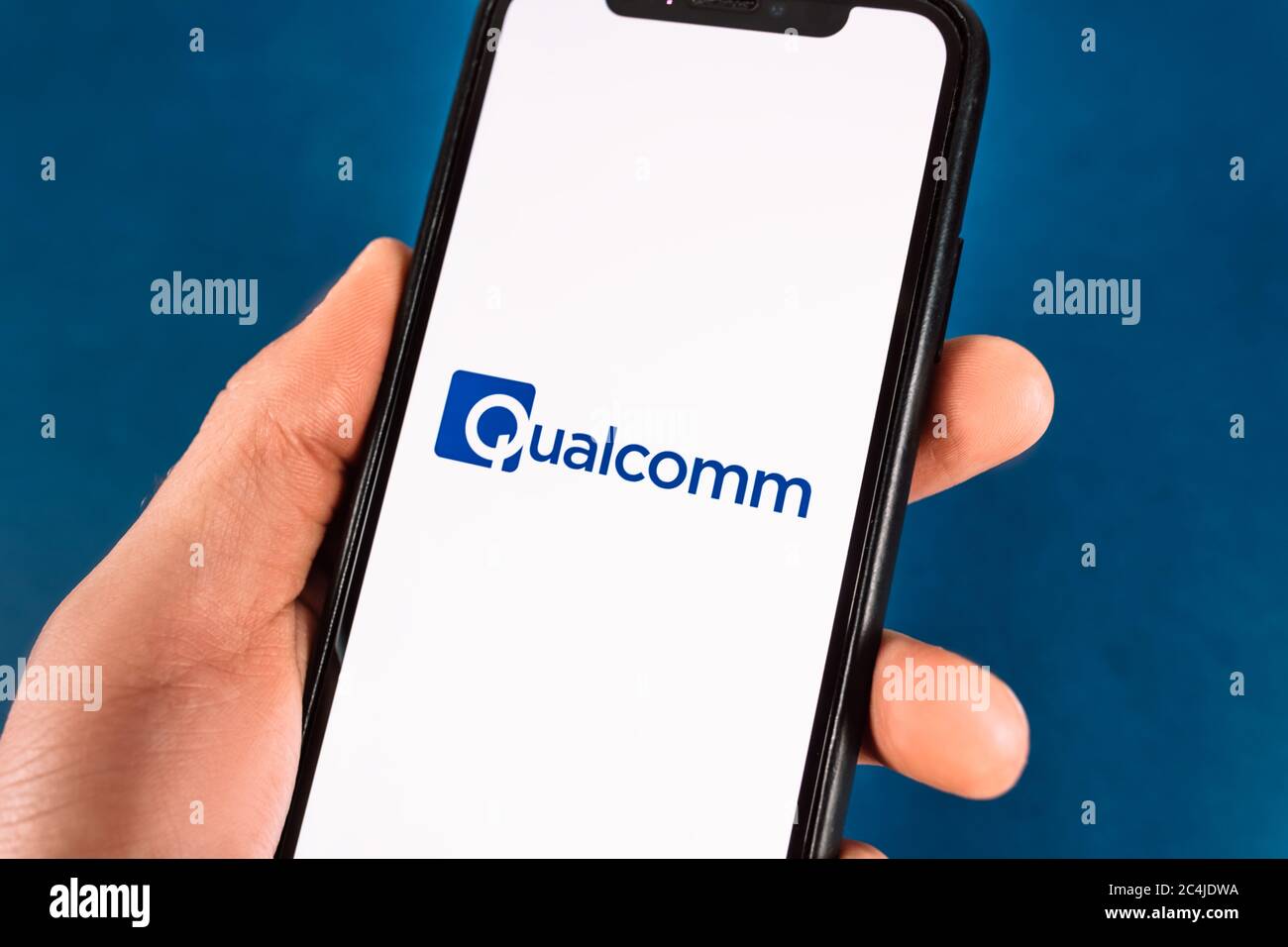 Die Hand hält das Smartphone mit qualcomm-Logo. Stockfoto