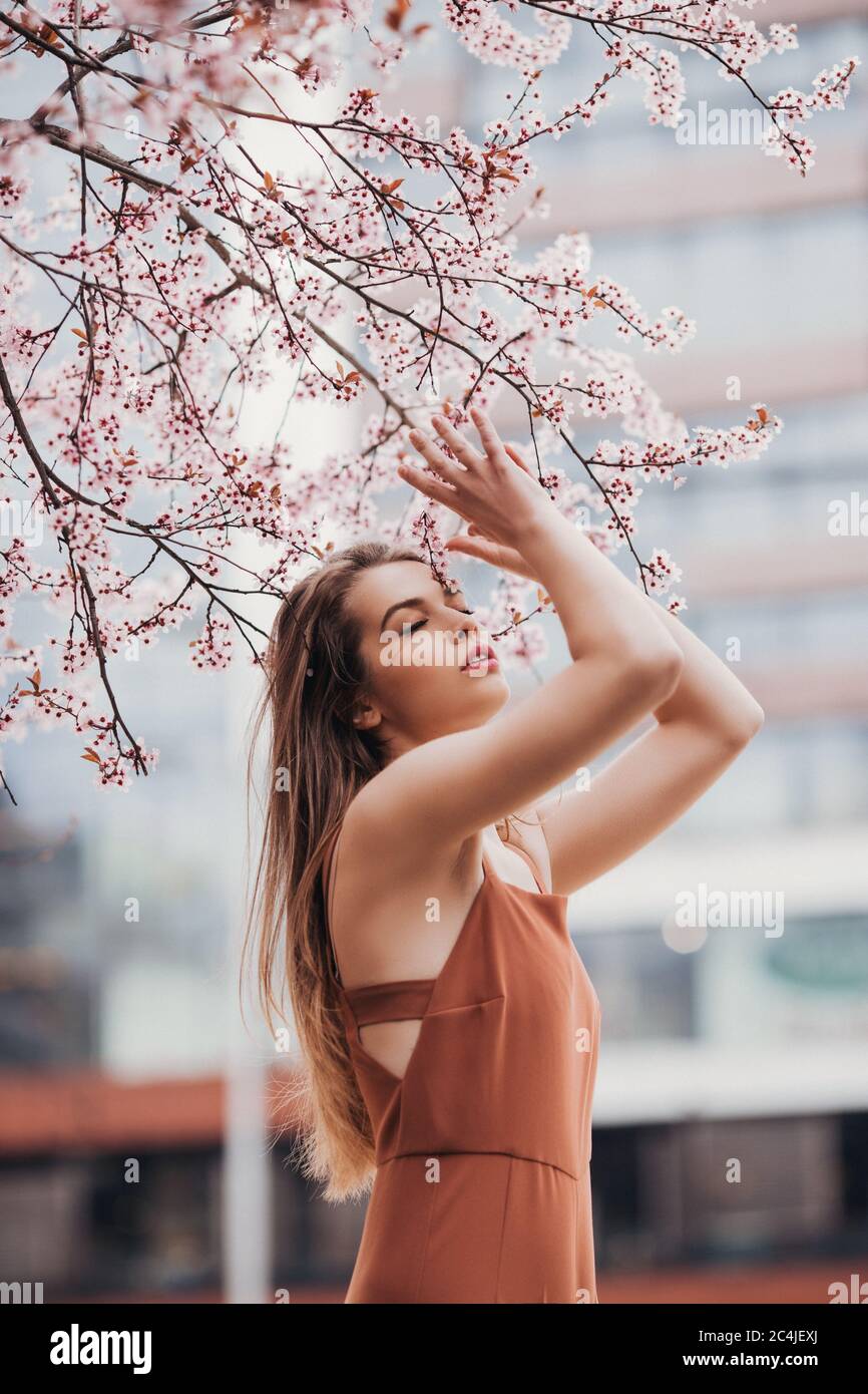 Fashion Portrait der jungen Frau im Jumpsuit unter der Blüte Baum Stockfoto