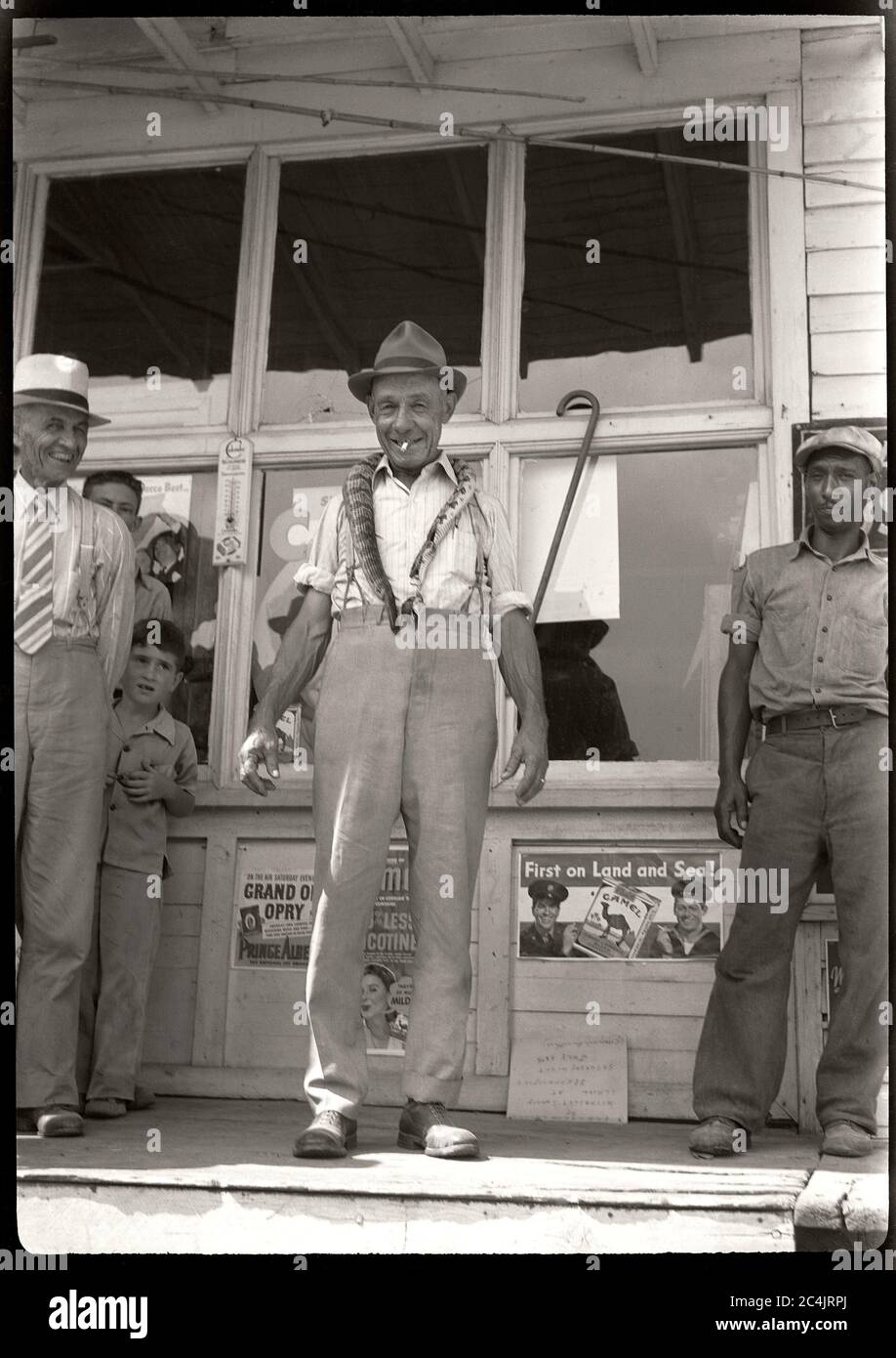 Mann, der vor dem Laden stand und eine Schlange um den Hals trug, um die 1940er Jahre. Bild von 2.5 x 3.5 Zoll Negativ. Stockfoto