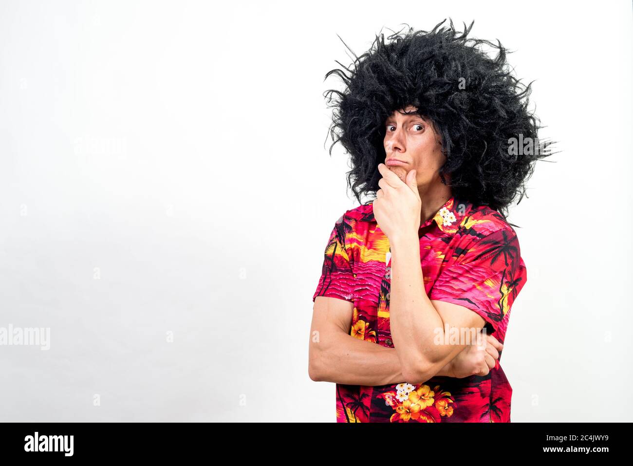 Mann in Afro Perücke und hawaiiihemd, sehr nachdenklich. Mittlerer Schuss. Weißer Hintergrund. Stockfoto