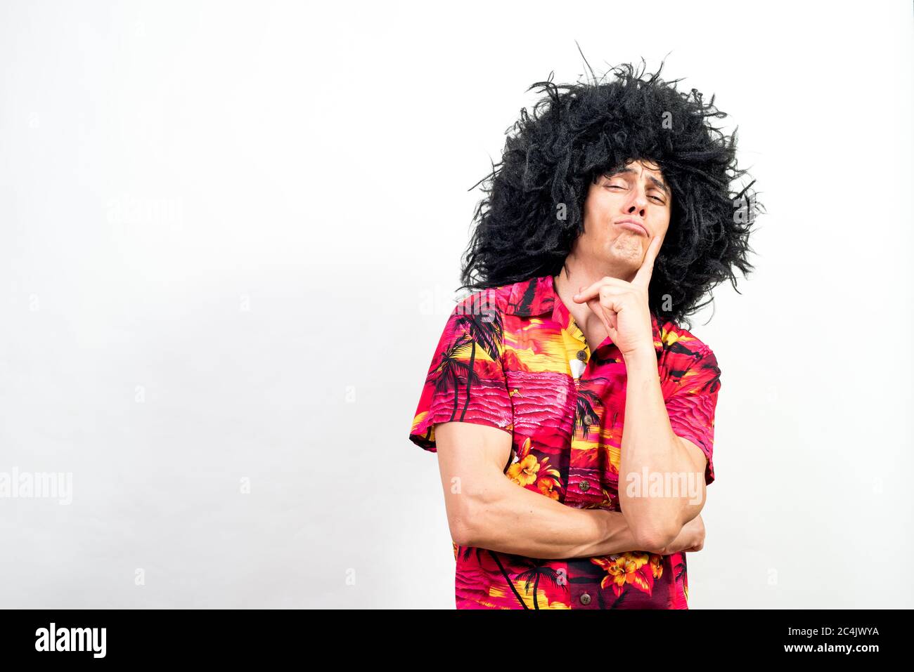 Mann in Afro Perücke und hawaiiihemd, sehr nachdenklich. Mittlerer Schuss. Weißer Hintergrund. Stockfoto