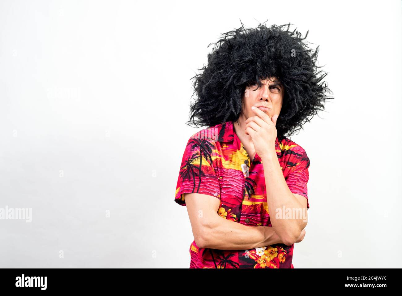 Mann in Afro Perücke und hawaiiihemd, sehr nachdenklich. Mittlerer Schuss. Weißer Hintergrund. Stockfoto