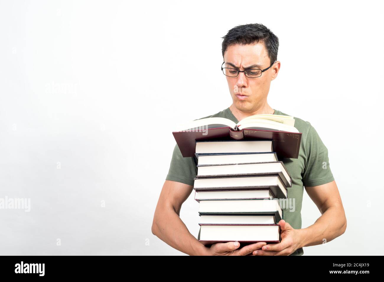 Konzentrierter Mann beim Lesen, während er einen Stapel Bücher hält. Mittlerer Schuss. Weißer Hintergrund. Stockfoto