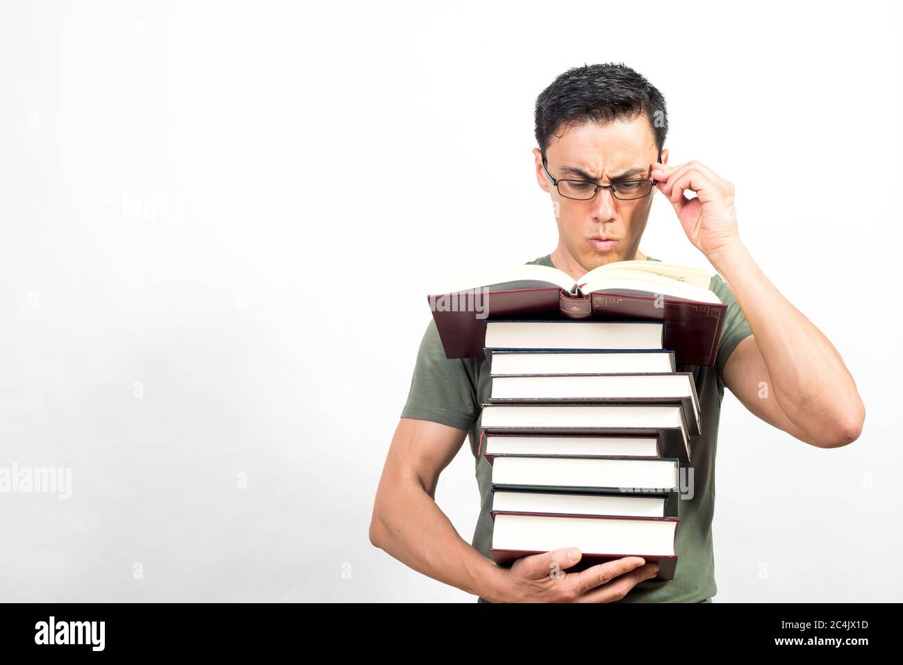 Konzentrierter Mann beim Lesen, während er einen Stapel Bücher hält. Mittlerer Schuss. Weißer Hintergrund. Stockfoto