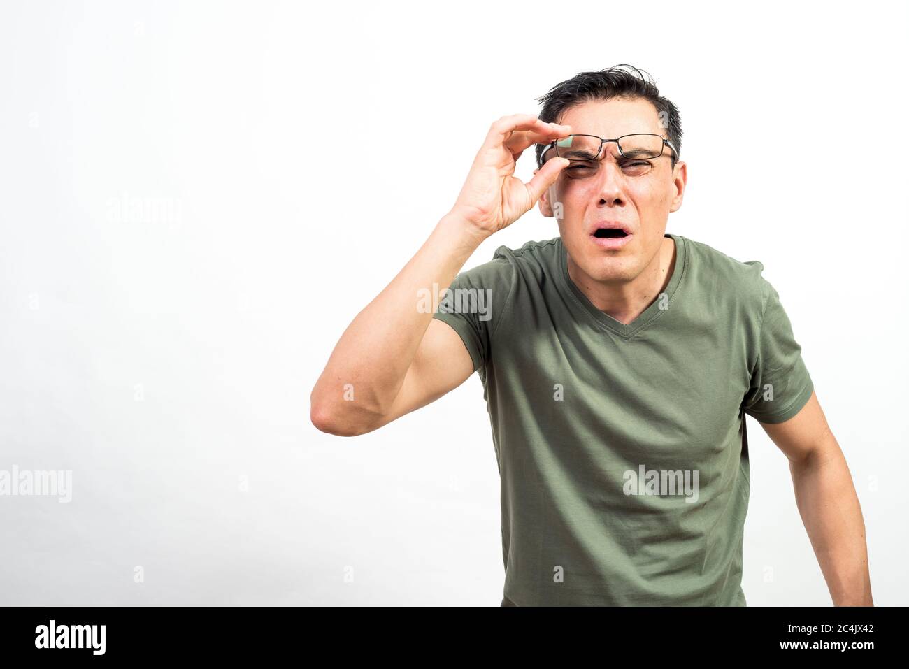 Mann mit Brille, die seine Augen belastet, weil er nicht gut sehen kann. Mittlerer Schuss. Weißer Hintergrund. Stockfoto