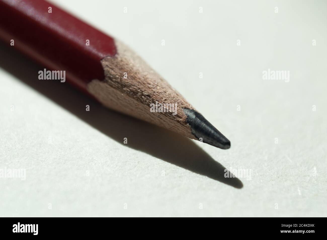 Nahaufnahme eines roten Holzbleistifts, der diagonal auf eine weiße Oberfläche gelegt wird. Stockfoto
