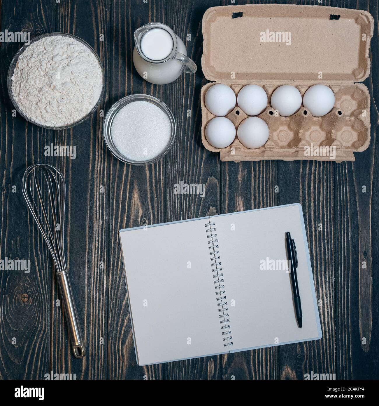 Leeres Rezeptbuch und Mehl, eeg, Milch, Zucker auf Holzhintergrund. Stockfoto