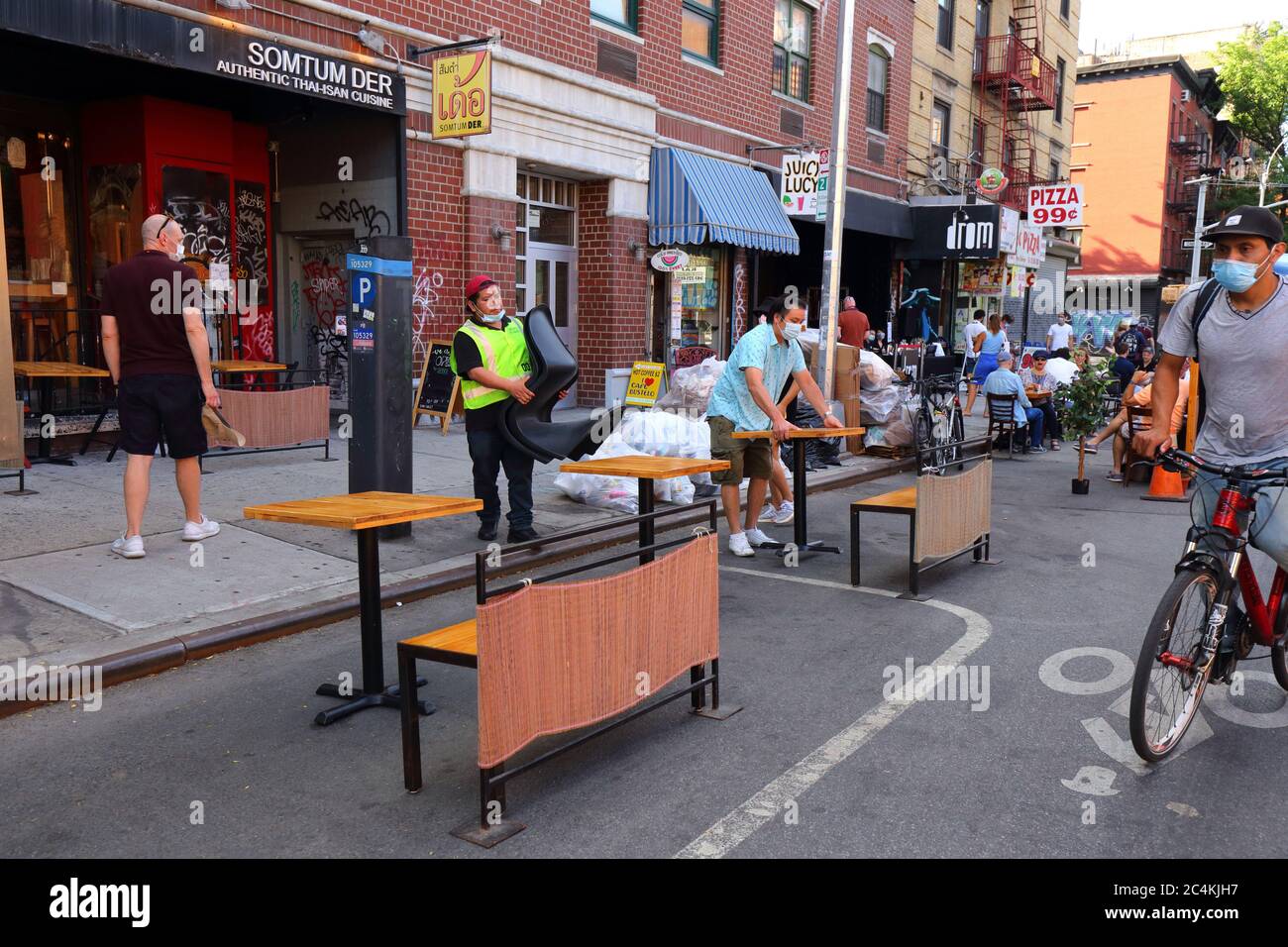 New York, NY, 25. Juni 2020. Arbeiter, die außerhalb von Sartum der auf einer belebten Avenue A im East Village im Rahmen der Phase 2 der Wiedereröffnung von New York City gesellschaftlich distanzierte Restaurants einrichten. Einige Restaurants und Bars haben die Kapazität erweitert, indem sie Parkwege in Parkhäuser umwandelten, Gehsteigeerweiterungen auf die Straße für Restaurants und Freizeit und nicht für die Autoaufbewahrung. Stockfoto