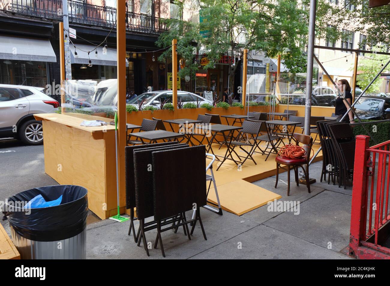 New York, NY, 26. Juni 2020. Ein Speisesaal mit Tischen, Stühlen und Plexiglas-Trennwänden wird vor einem Restaurant in Nolita im Rahmen der Phase 2 Wiedereröffnung von New York City eingerichtet. Einige Restaurants und Bars haben die Kapazität erweitert, indem sie Parkwege in Parkhäuser umwandelten, Gehsteigeerweiterungen auf die Straße für Restaurants und Freizeit und nicht für die Autoaufbewahrung. Stockfoto