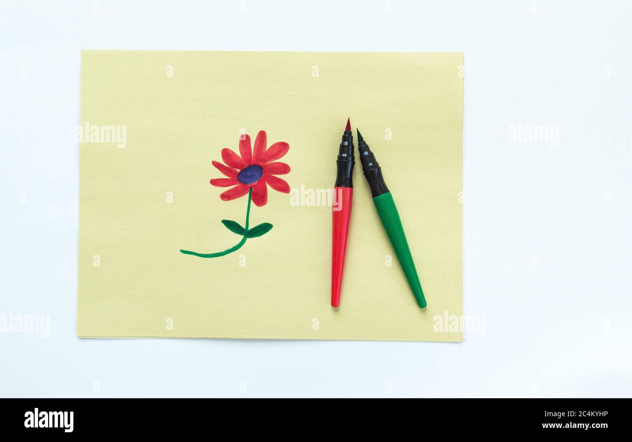 Kinderzeichnung einer roten Blume auf gelbem Papier mit zwei Tintenmarkern, isoliert auf Weiß Stockfoto