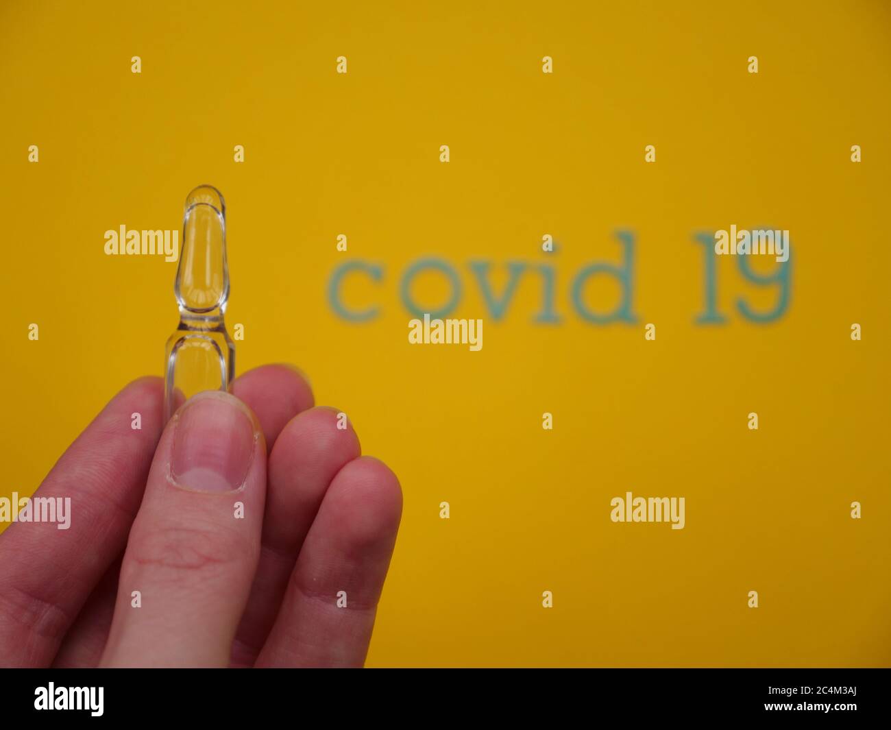 Ampulle auf gelbem Hintergrund zur Behandlung von Coronavirus Covid19 Stockfoto