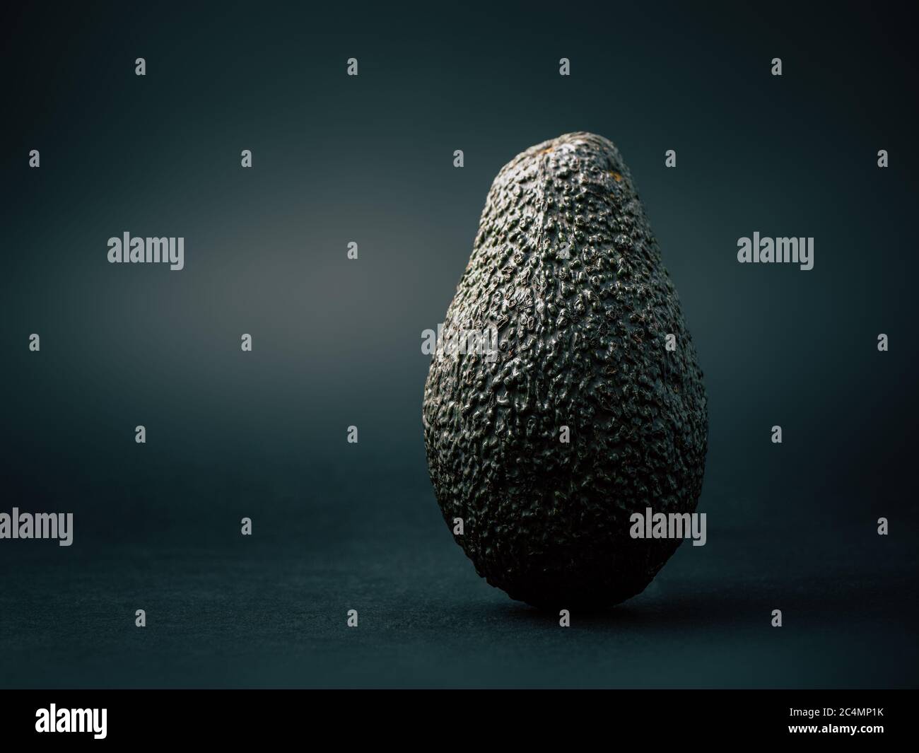 Filmische Avocado-Studiofotografie, isoliert auf einem dunklen Hintergrund, mit einer rauen und holprigen Textur Stockfoto