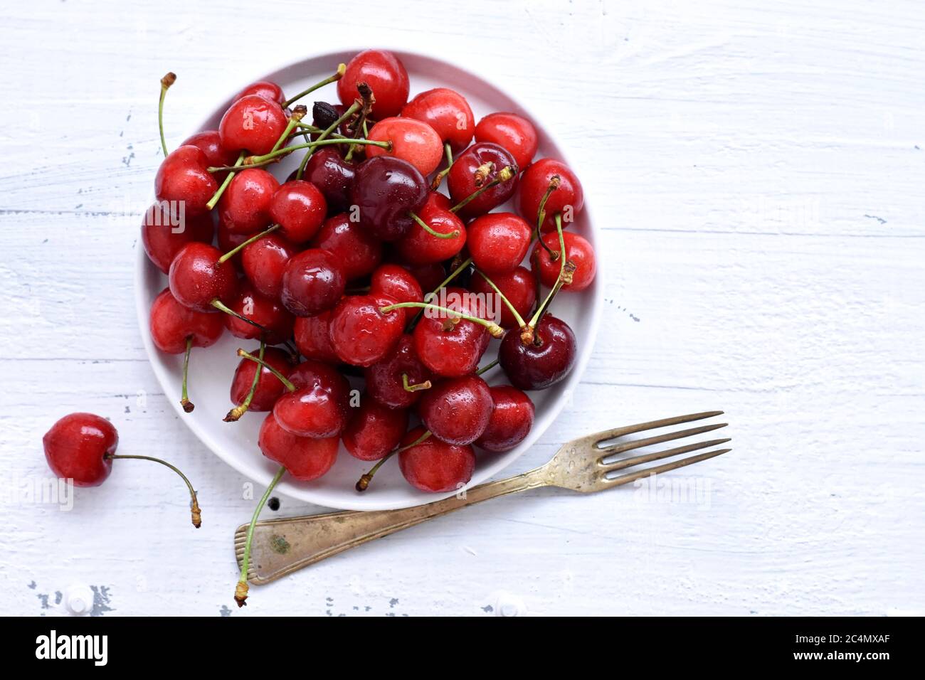 Frische saftige rote Kirschen isoliert auf weißem Hintergrund / rote frische Kirschen süße Kirschen Beeren auf weißem Holz Hintergrund Stockfoto