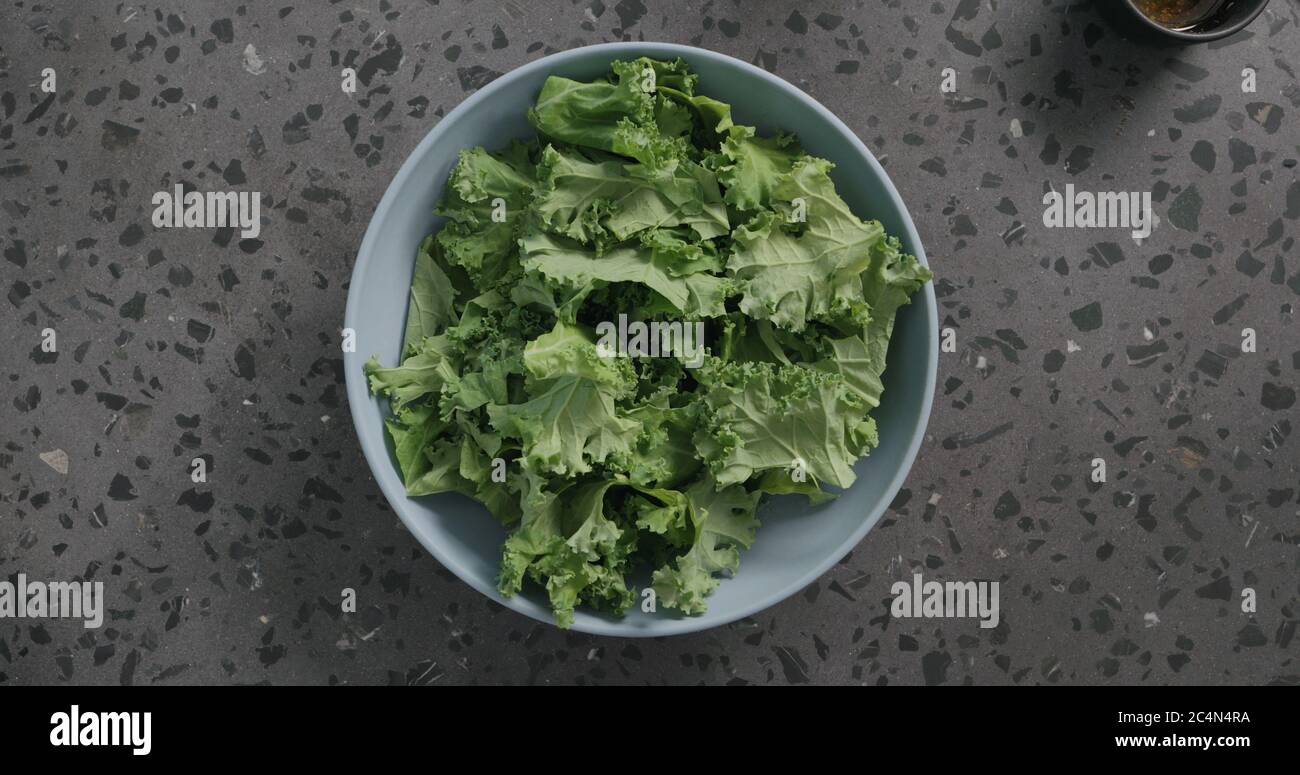kale Blätter in blauer Keramikschale auf Beton Hintergrund Stockfoto