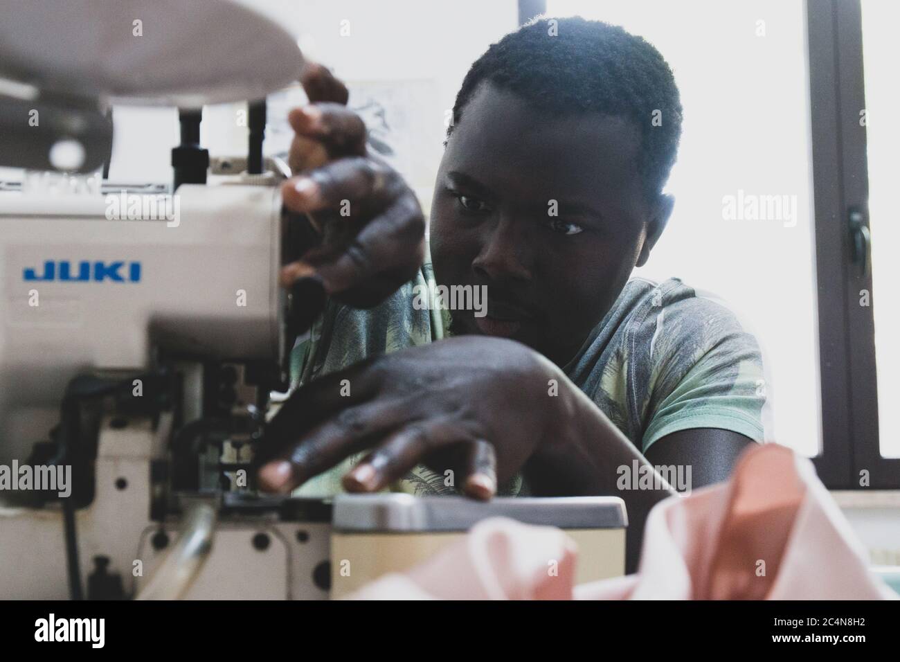 Politische Flüchtlinge und afrikanische Einwanderer arbeiten an der Schneiderei der gemeinnützigen Vereinigung im Süden Italiens, Neapel. Stockfoto