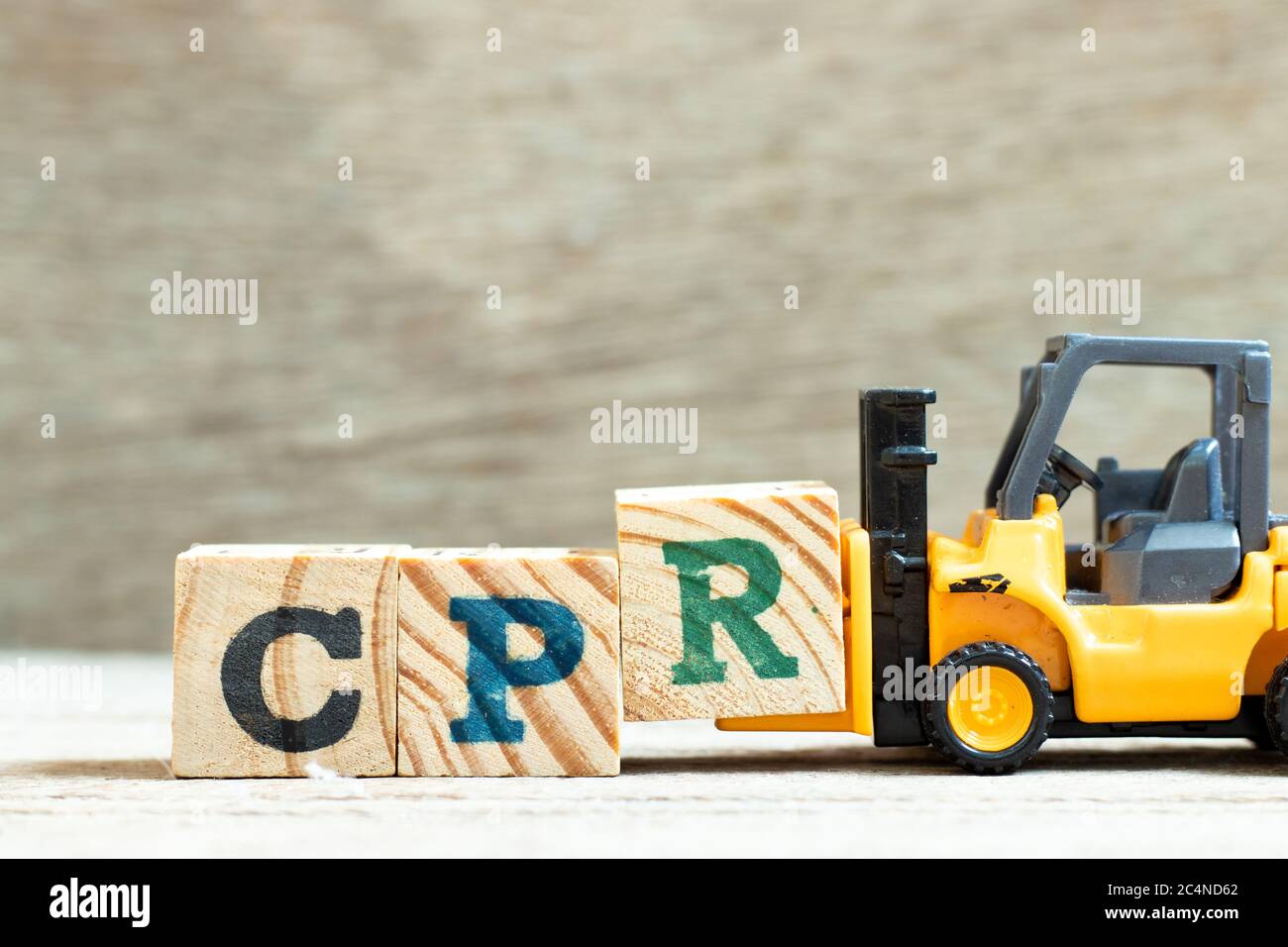Spielzeug Gabelstapler halten Buchstabenblock R, Wort CPR (Abkürzung von Cardiopulmonary Reanimation) auf Holzhintergrund zu vervollständigen Stockfoto