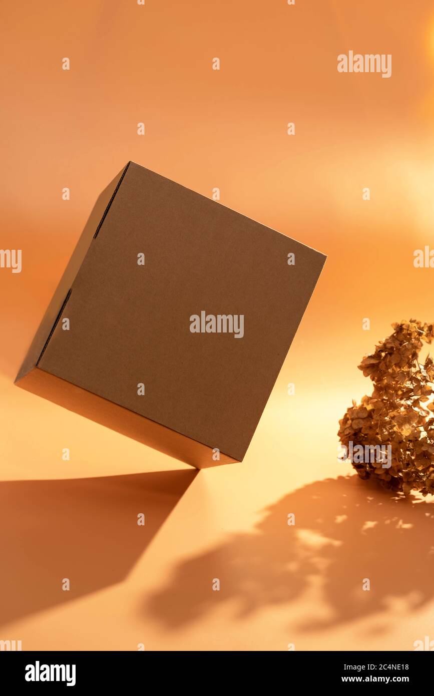 Karton auf dem Tisch. Steht auf einer Kante. Warme Farben. Lieferkonzept. Stockfoto