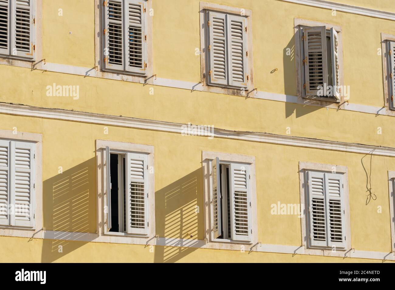Traditionelles Gebäude im mediterranen Stil mit weißen Fensterläden an der gelben Wand Stockfoto
