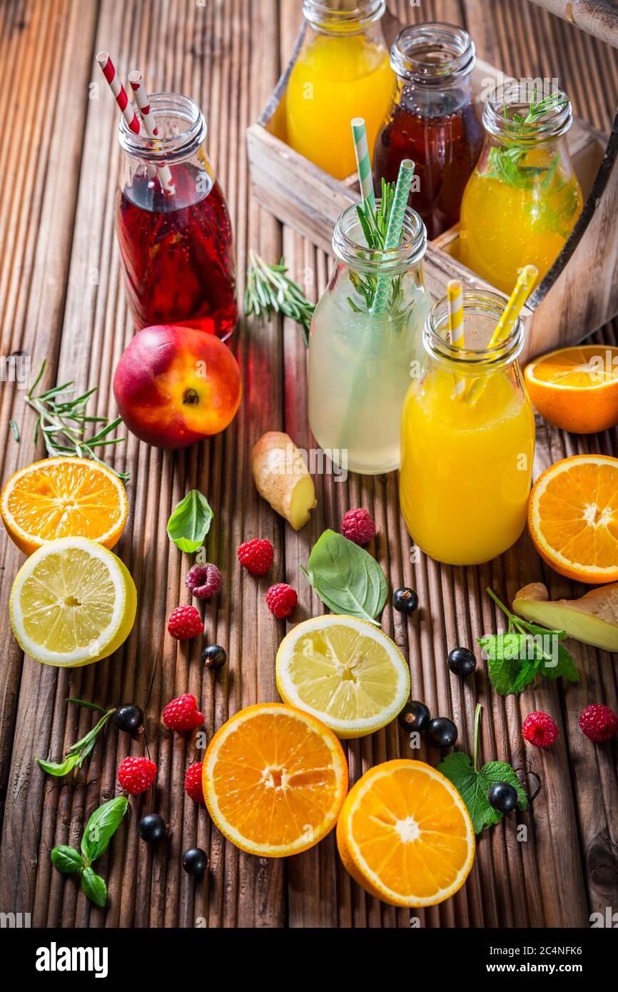 Auswahl an Säften und Limonaden mit Früchten und Kräutern auf Holztisch Stockfoto