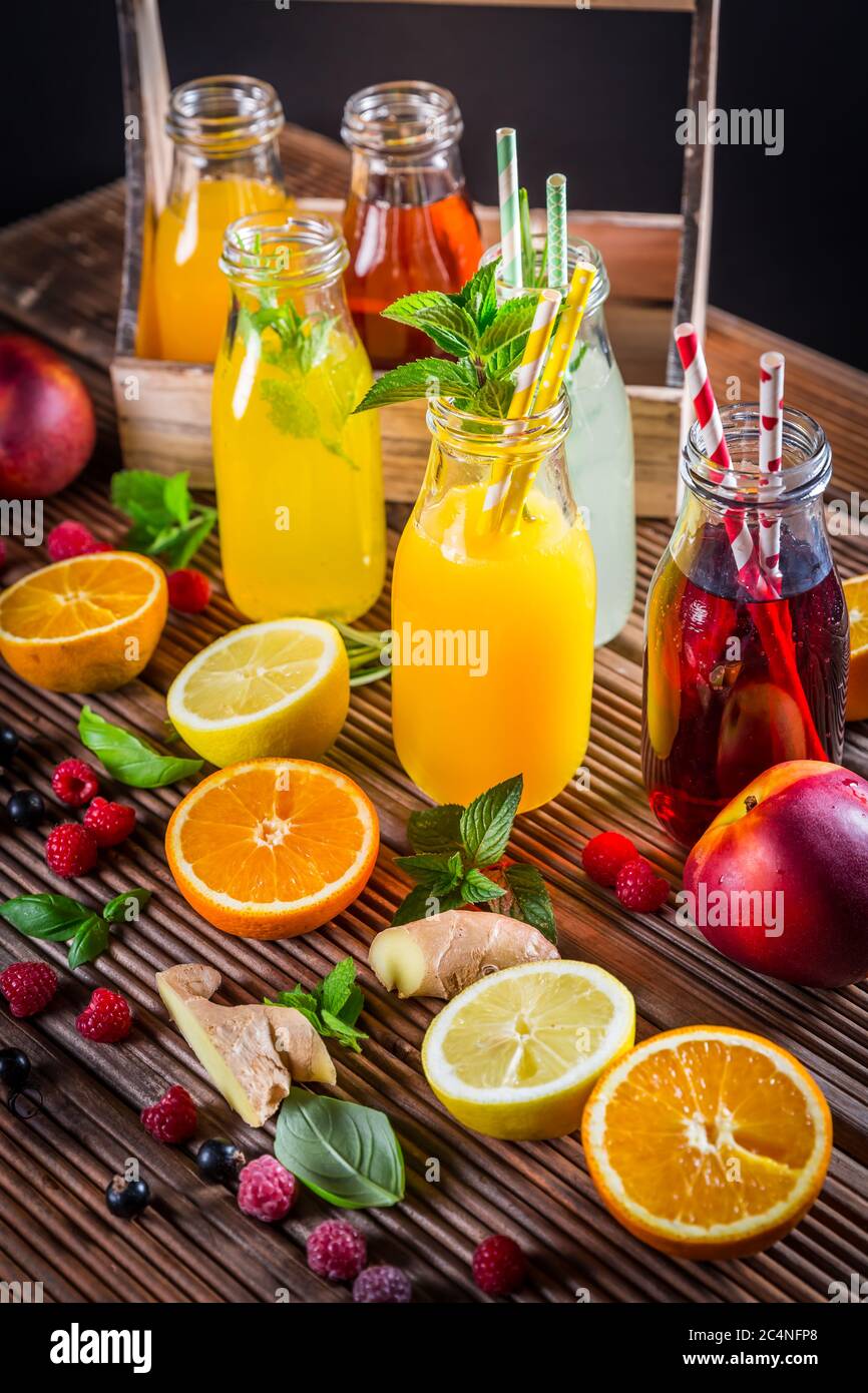 Auswahl an Säften und Limonaden mit Früchten und Kräutern auf Holztisch Stockfoto
