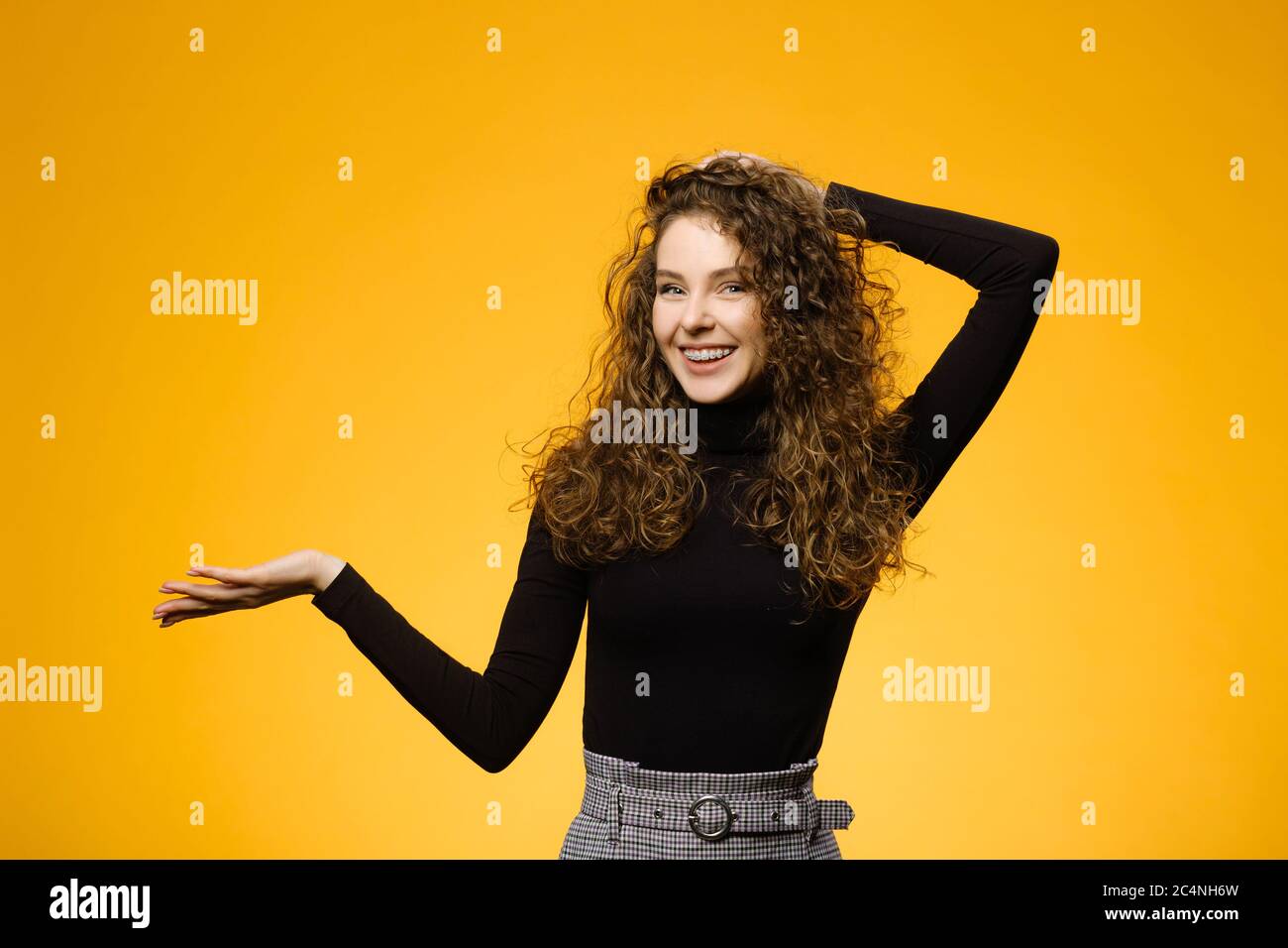 Hübsches Mädchen mit lockigen Haaren isoliert auf gelbem Hintergrund. Modell mit Langarm-Shirt Stockfoto