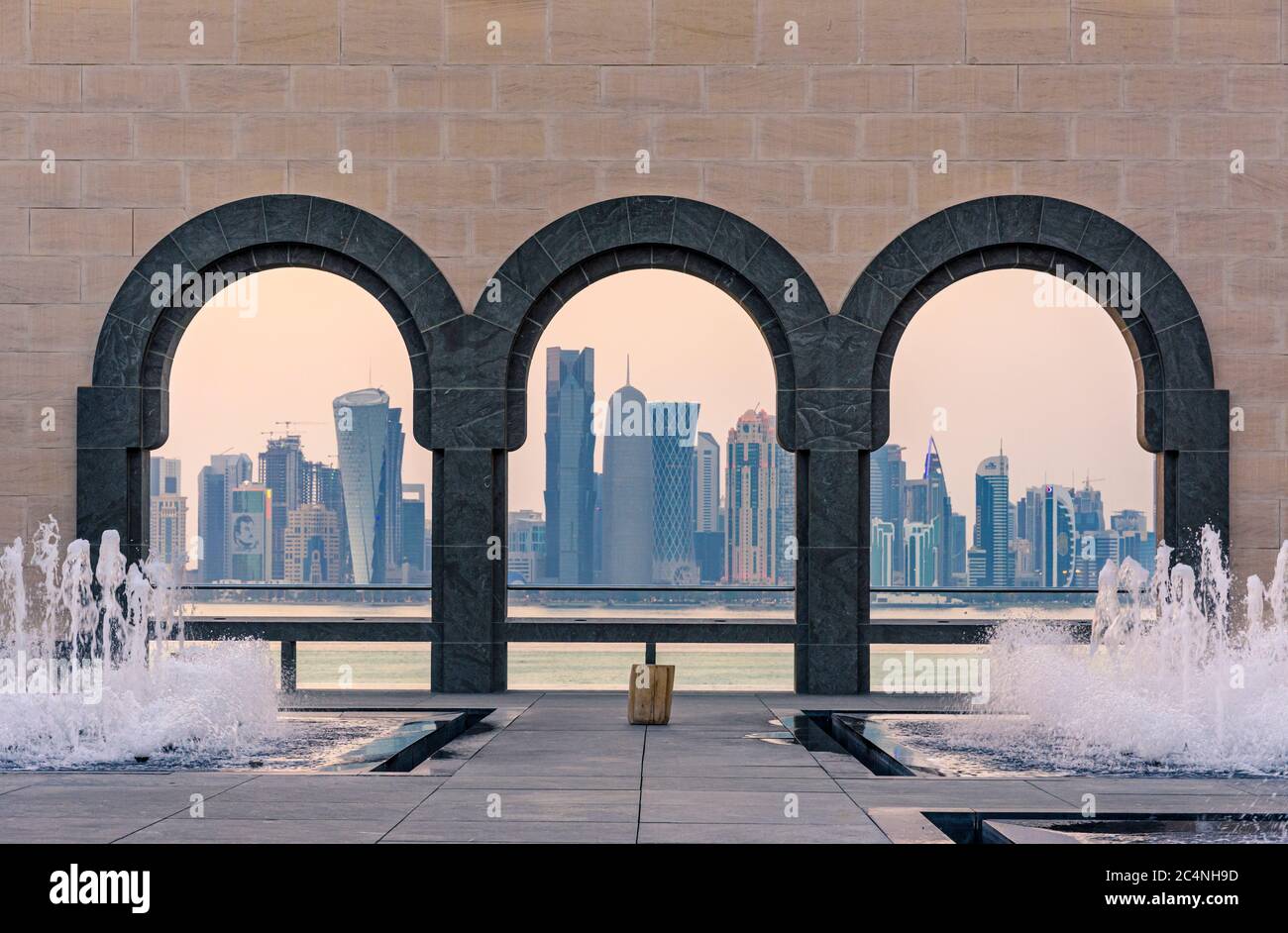 Blick auf die Skyline von Doha bei Sonnenuntergang durch die Bögen des Innenhofs im Museum für Islamische Kunst, Doha, Katar Stockfoto