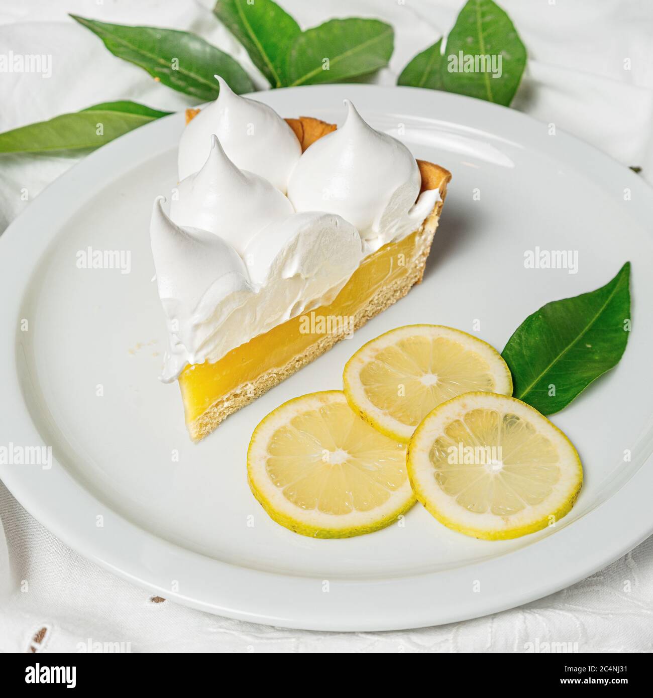 Stück Zitronenkuchen mit einem Mousse Belag in einem Platte unter den Lichtern Stockfoto