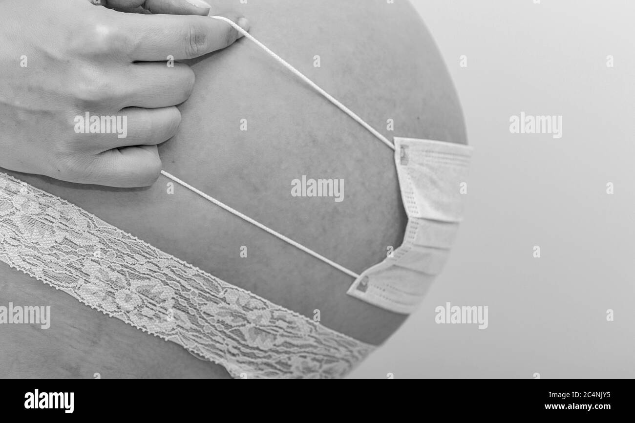 Covid 19 ncov Coronavirus und Pandemievirus Symptome. Nahaufnahme der schwangeren Bauch mit OP-Maske zum Schutz Bauch Baby. Beenden Sie die Quarantäne. Stockfoto