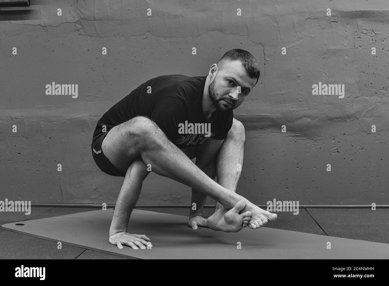 Sportlicher junger Mann beim Training, beim Handstand Yoga. Studio in städtischen Fitness-Studio mit grauem Hintergrund für Kopierraum aufgenommen. Stockfoto