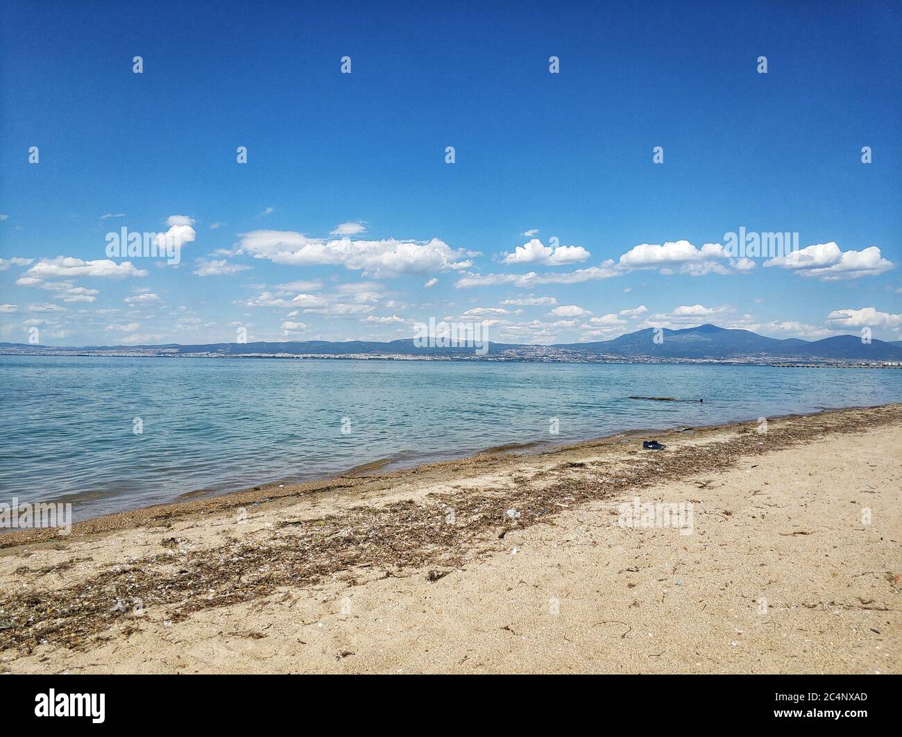 Breite Aufnahme des Strandes mit blauem Wasser und Sommerhimmel In der Gegend von Thessaloniki in Griechenland Stockfoto