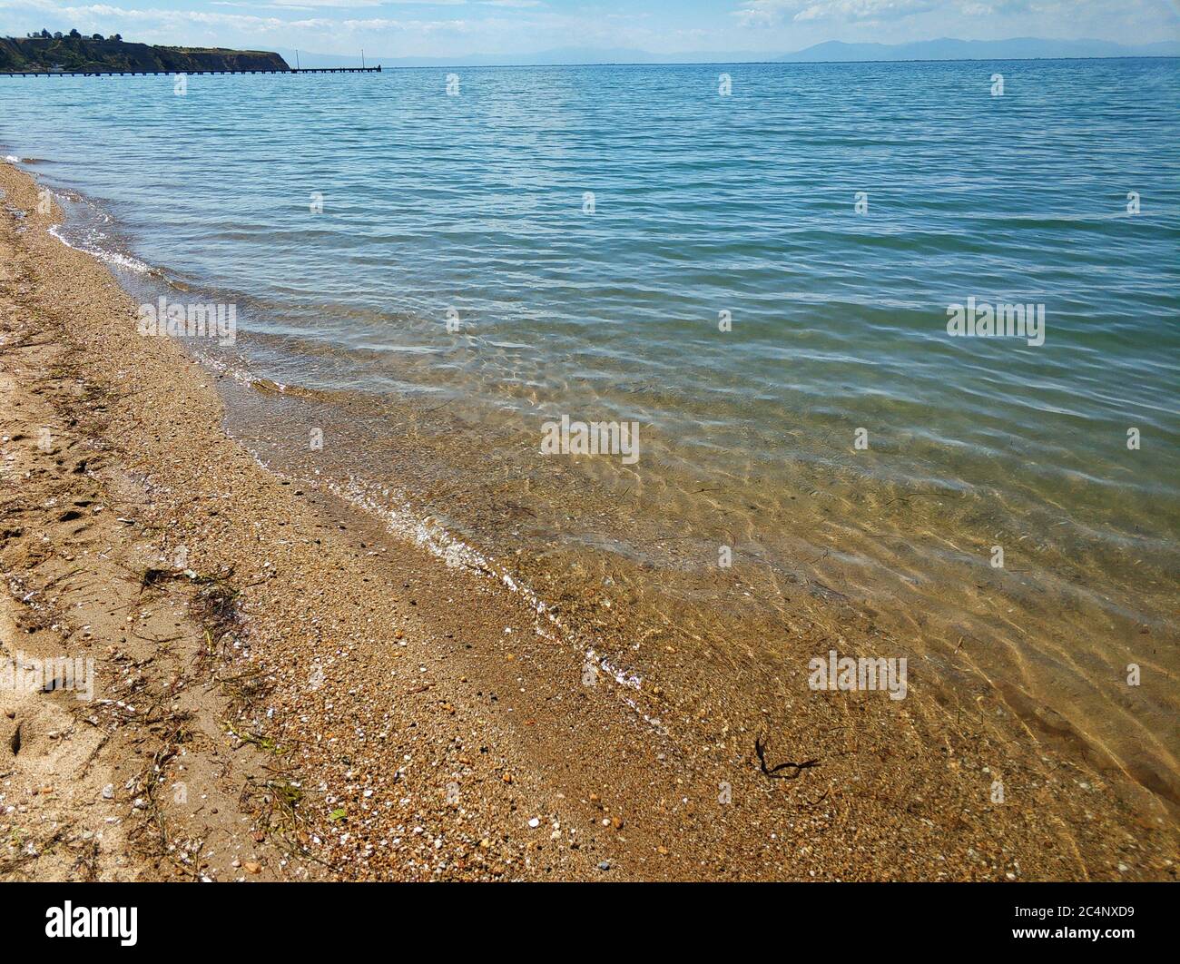 Breite Aufnahme des Strandes mit blauem Wasser und Sommerhimmel In der Gegend von Thessaloniki in Griechenland Stockfoto