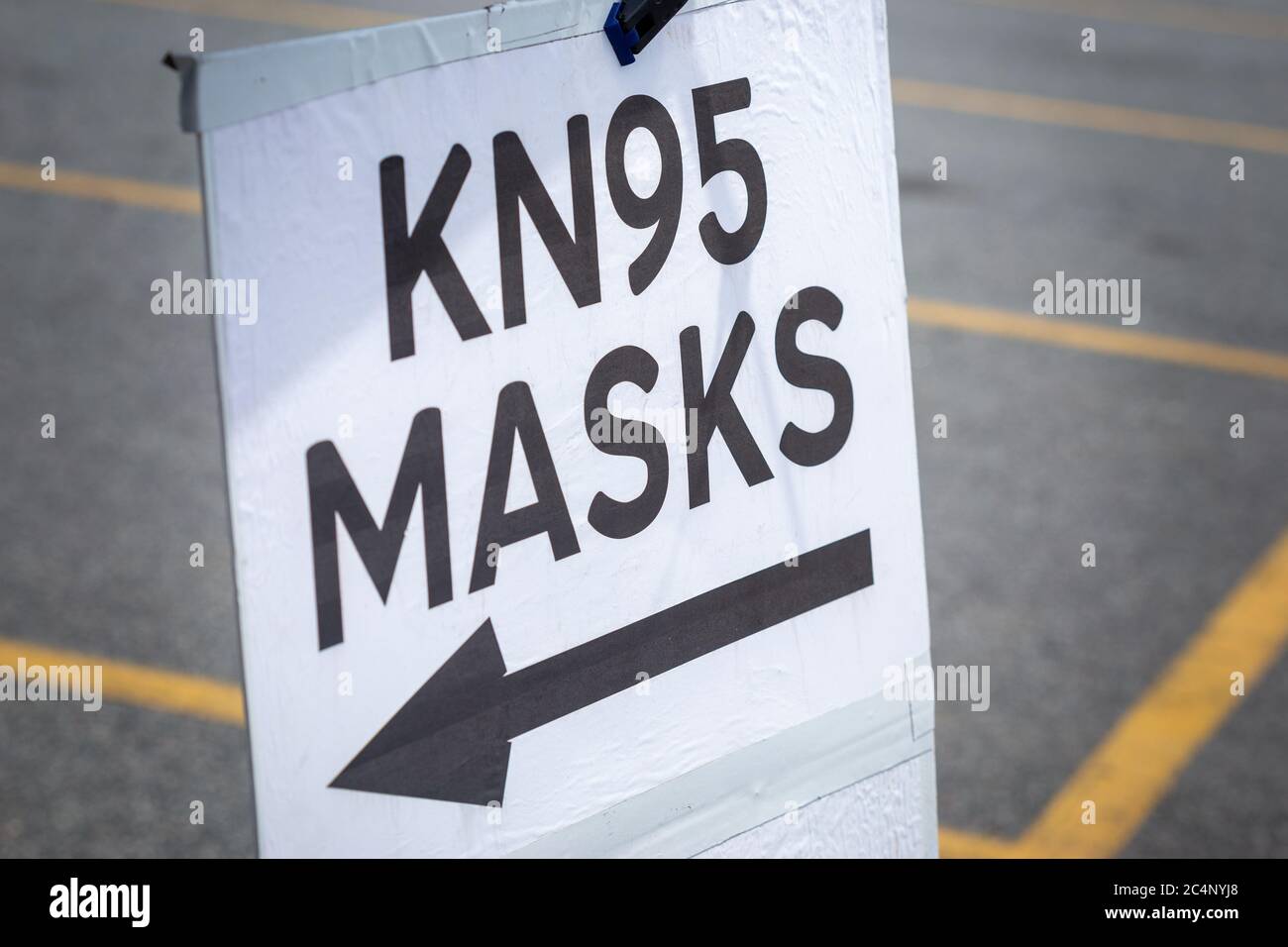 Angewinkeltes KN95 Maskenposter, das an einem Pop-up-Handdesinfektionsgerät auf dem Parkplatz angebracht ist Stockfoto