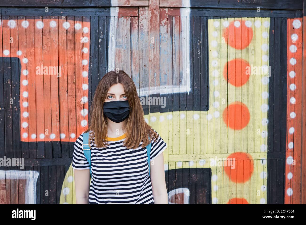 Frau trägt Maske stehen gegen farbige Stadtmauer Stockfoto